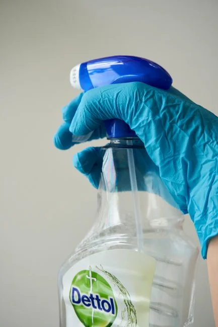 Person in PPE disinfecting indoor window area during COVID-19 pandemic.
